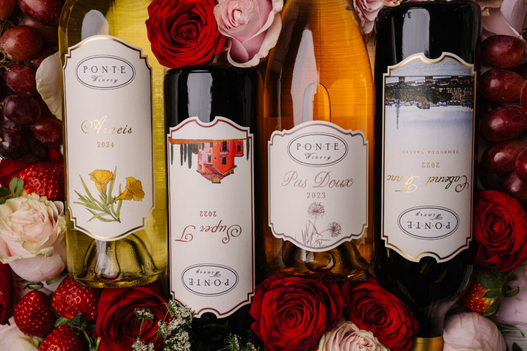 4 bottles of wine on a bed of roses and strawberries