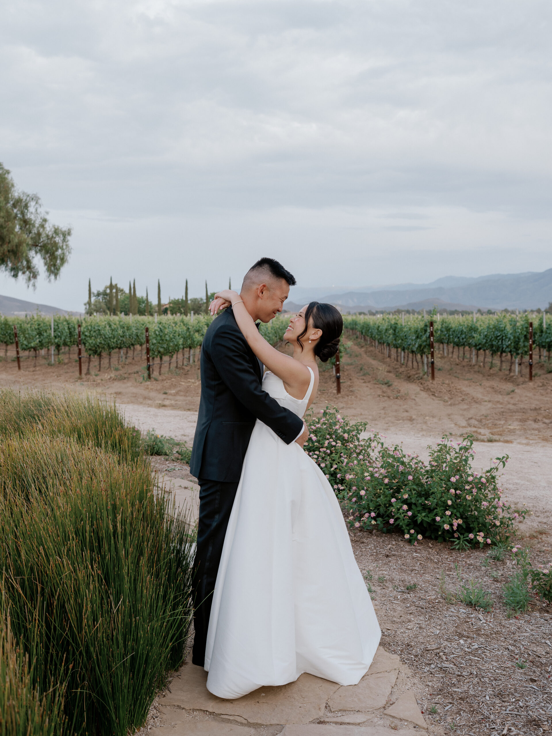 wedding couple smiling at each other in the vineyard for a photo